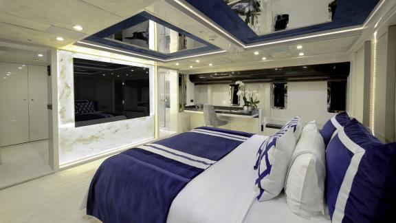 Luxurious bedroom with comfortable king-size bed and fine royal blue bed linen under a mirrored ceiling.